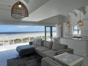 a living room with a couch and a view of the beach at Paternoster Penthouse - Solar in Paternoster