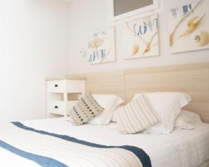 a bedroom with a bed with white sheets and pillows at Hotel La Ciotat - A deux pas de l'eau in La Ciotat