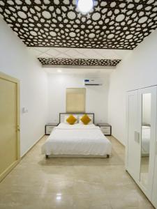 a bedroom with a white bed with two yellow pillows at EK Homes in Ras al Khaimah