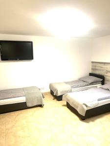 una camera con tre letti e una TV a schermo piatto di Hostel 24 Miejsca Parkingowe Noclegi Pracownicze. a Gorzów Wielkopolski