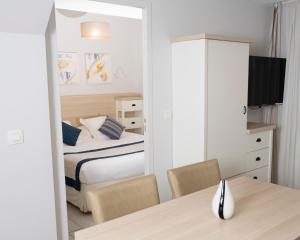 a bedroom with a bed and a table and chairs at Hotel La Ciotat - A deux pas de l'eau in La Ciotat