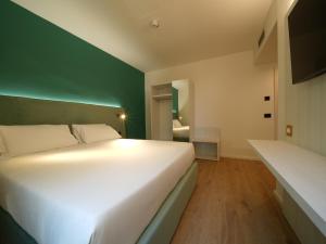 a bedroom with a white bed and a green wall at Castiglioncello Suite in Castiglioncello