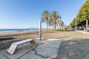 a bench on a beach with palm trees and the ocean at Casa Coral Beach in Málaga