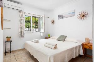 a white bedroom with a bed with two towels on it at Villa Bienvenidos in Son Bou +19 photos