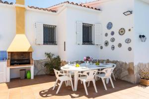 a patio with a table and chairs and a white wall at Villa Bienvenidos in Son Bou