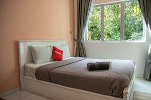 a bedroom with a bed with two pillows and a window at A3A Oastel coLiving in Tanah Rata