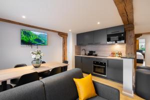 eine Küche und ein Wohnzimmer mit einem Tisch und einer Couch in der Unterkunft Homaris Apartments München Laim in München
