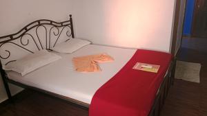 una cama pequeña con una manta roja y una camisa encima. en Vincent's Holiday Home, en Baga