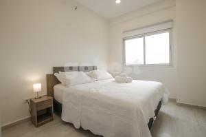 a white bedroom with a large bed with a window at Comfortable Apartment Close To Shopping Mariscal in Asunción