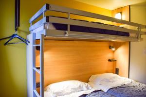 a bedroom with a bunk bed with a wooden headboard at Premiere Classe Rodez in Rodez