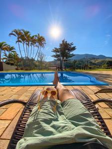 a man laying on a raft next to a swimming pool at Pousada Flores do Campo in Águas de Lindoia