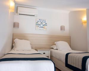 two beds in a small room with white walls at Hotel La Ciotat - A deux pas de l'eau in La Ciotat