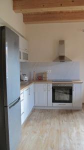 a kitchen with white cabinets and a black refrigerator at Apartmány LehotSKI Guest House in Pavčina Lehota