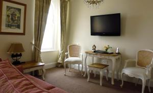 a living room with a tv and a table and chairs at The Town House in Douglas