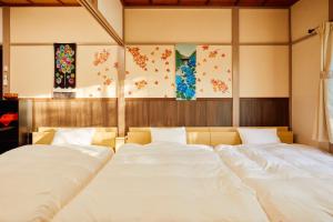 two large white beds in a room with paintings at Villa Hakone Kabuto 古民家旅館 150平米 バス停迄一分 準天然温泉 最大12名 in Sekishoato