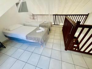 sypialnia z 2 łóżkami i podłogą wyłożoną kafelkami w obiekcie Bel appartement cosy - Les pieds dans l'eau w mieście Le Gosier