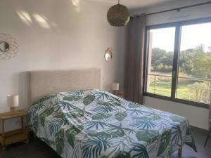 a bedroom with a bed with a colorful comforter and a window at Domaine d'Arca - Flaubert 11 - 4 pers - étage 1 in Porto-Vecchio