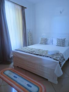 1 dormitorio con 1 cama blanca grande y ventana en Olive Branch home, en Mombasa