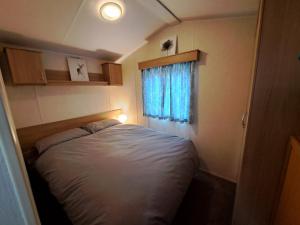 um pequeno quarto com uma cama e uma janela em Cosy home with stunning views em Holsworthy