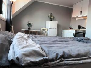 een ongemaakt bed in een kamer met een keuken bij cozy studio apartment in Trondheim
