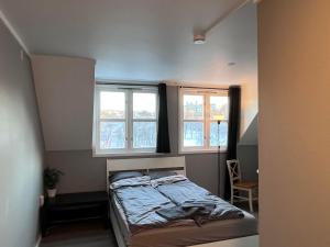 een slaapkamer met een bed en 2 ramen bij cozy studio apartment in Trondheim