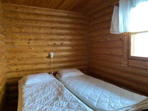 um pequeno quarto com uma cama num chalé de madeira em Kuusivilla 1 em Syöte