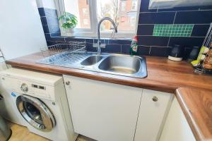 een keuken met een wastafel en een wasmachine bij Captivating 4-Bed House in Cheltenham in Cheltenham