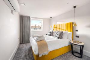 - une chambre avec un grand lit et une tête de lit jaune dans l'établissement Kentish Town Road, à Londres