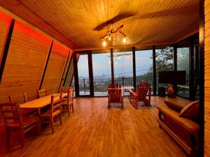 Dream Panorama Cottage في باتومي: غرفة طعام مع طاولة وكراسي ونوافذ