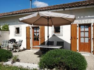 a table with an umbrella in front of a house at La Vieille Gorce Gîtes in the Vienne in Asnois