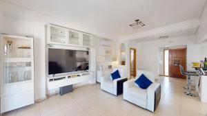 a living room with two white chairs and a large television at La Torre Villa Bacalao - A Murcia Holiday Rentals Property in Roldán