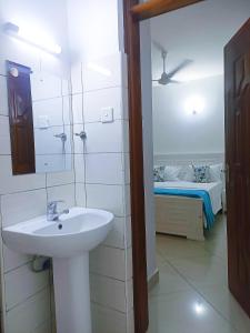 baño con lavabo, espejo y cama en Olive Branch home, en Mombasa