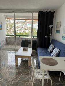 ein Wohnzimmer mit einem blauen Sofa und einem Tisch in der Unterkunft La Cascada 410 in Puerto Rico de Gran Canaria