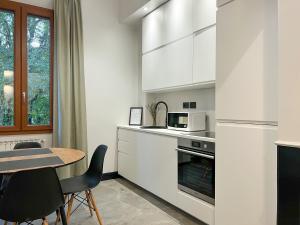 une cuisine avec des placards blancs et une table avec des chaises dans l'établissement Mondo7, à Bologne