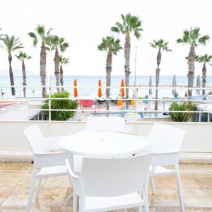 a white table and chairs with the beach in the background at Hotel La Ciotat - A deux pas de l'eau in La Ciotat