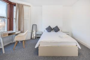 a bedroom with a bed and a desk and a chair at Bright Guest house in Stratford in Stratford