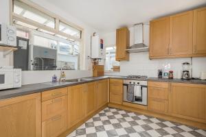 a kitchen with wooden cabinets and a checkered floor at Bright Guest house in Stratford in Stratford