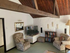 ein Wohnzimmer mit einem Flachbild-TV und 2 Stühlen in der Unterkunft Cider Cottage - 3 Bedroom - Onsite Parking in Sidmouth + 33 Fotos