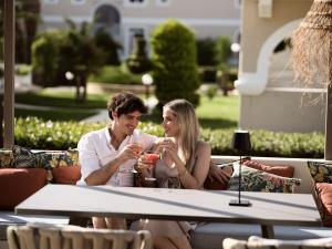 a man and woman sitting at a table drinking wine at Marelen Hotel Zakynthos in Kalamaki