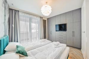 a bedroom with two beds and a tv and a chandelier at Apartamenty Sun & Snow Ogrodowa in Sopot