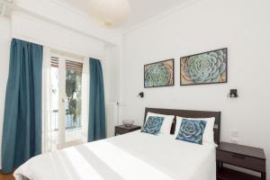 a bedroom with a bed with blue curtains and a window at Seafront Apartment in Piraeus in Piraeus