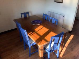 una mesa de madera con sillas azules y un bol en ella en Cider Cottage - 3 Bedroom - Onsite Parking, en Sidmouth