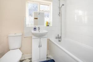 a bathroom with a toilet and a sink and a bath tub at Bright Guest house in Stratford in Stratford