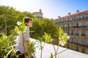 uma mulher em pé em cima de um edifício com flores em The People - Marseille em Marselha