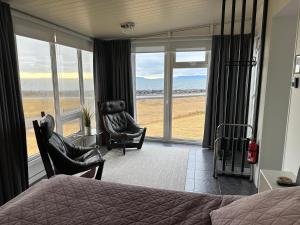a bedroom with a bed and chairs and a view of the ocean at Sol apartment in Keflavík