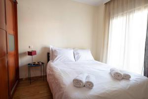 sypialnia z białym łóżkiem i ręcznikami w obiekcie Cozy apartment in Sykies w Salonikach