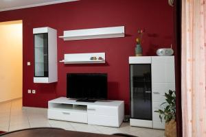 salon z telewizorem na czerwonej ścianie w obiekcie Cozy apartment in Sykies w Salonikach