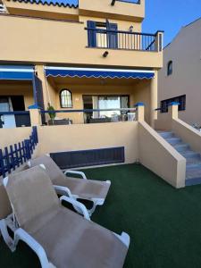 a balcony of a building with chairs and stairs at Triplex Meloneras-Amplio,soleado in Maspalomas
