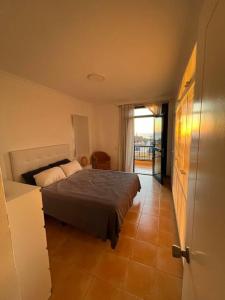 a bedroom with a bed and a view of a balcony at Triplex Meloneras-Amplio,soleado in Maspalomas
