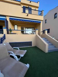 a balcony of a house with white chairs and stairs at Triplex Meloneras-Amplio,soleado in Maspalomas